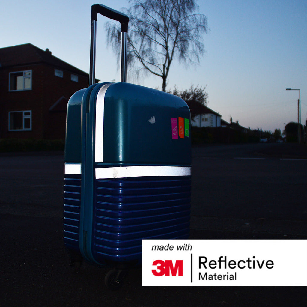 Image of silver reflective tape attached to a suitcase outside in low lighting. 